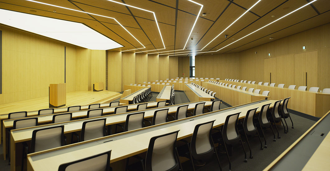 Life Campus Auditorium 강의시설 목재 마감 강의실에 계단식 좌석과 중앙 통로, 발표 단상을 갖춘 Life Campus Auditorium 내부