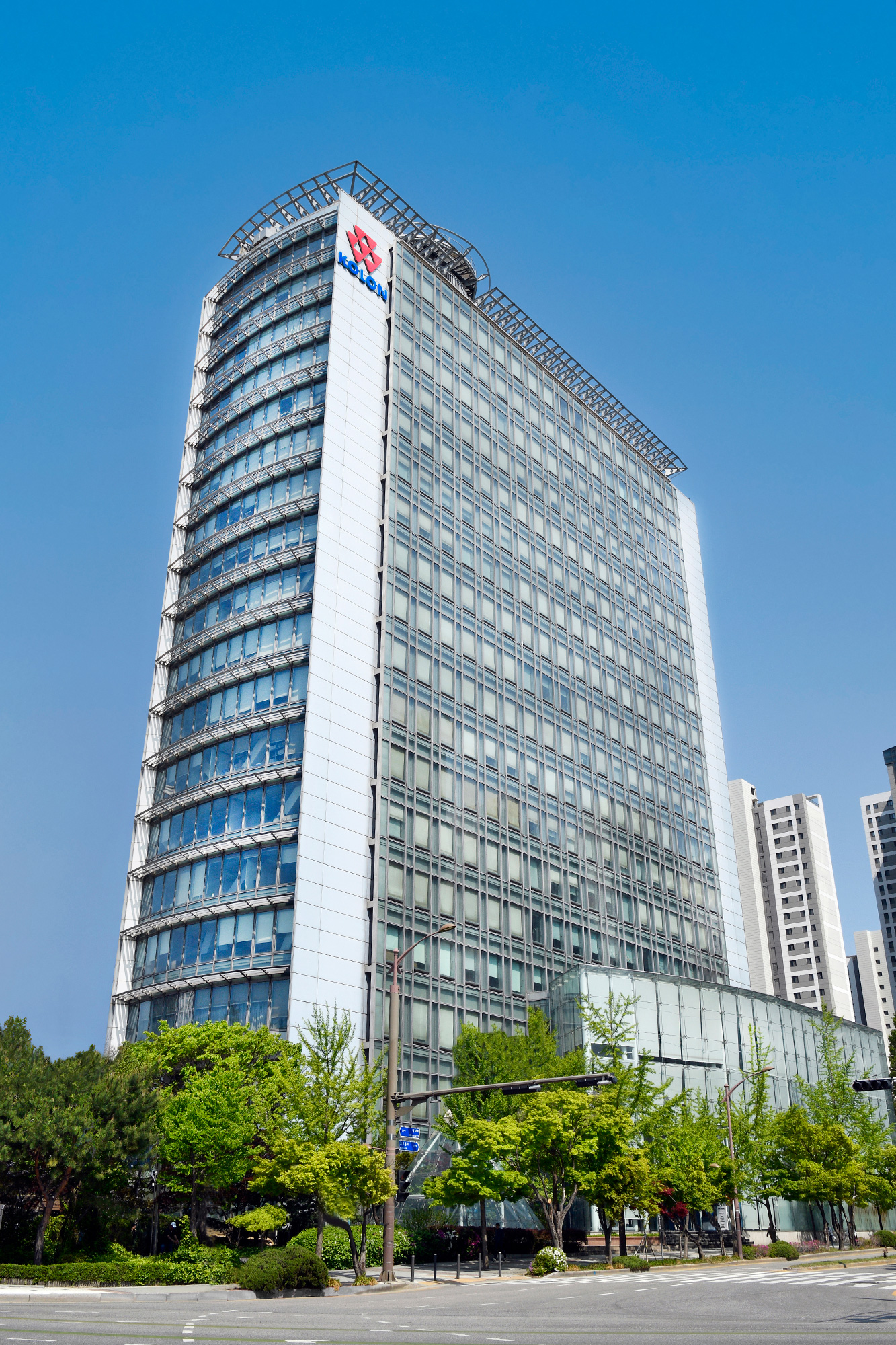 파란 하늘 아래 코오롱 로고가 설치된 유리 외관의 고층 사옥