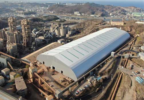 삼표시멘트 대규모 생산시설과 밀폐형 저장 설비 산업설비와 대형 흰색 밀폐형 저장 건물이 있는 삼표시멘트 생산시설 전경