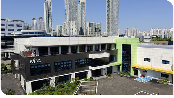 엔에프씨 본사 및 제1공장 전경 NFC 로고가 있는 검은색과 연두색 외벽의 본사 및 제1공장 건물 전경