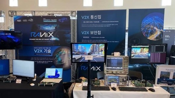 V2X 통신·보안칩 기술 전시 부스 라닉스 V2X 통신칩과 보안칩 전시 패널, 계측기와 모니터가 놓인 기술교류회 부스