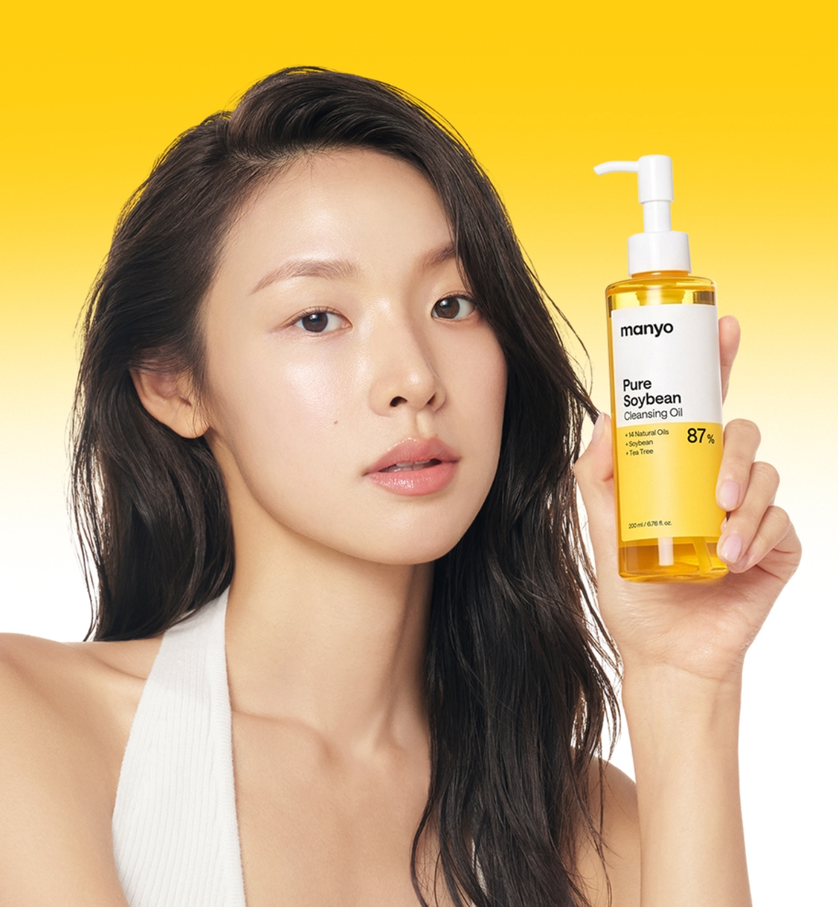 마녀공장 퓨어 소이빈 클렌징 오일 노란 배경에서 모델이 마녀공장 퓨어 소이빈 클렌징 오일 펌프 용기를 들고 있는 사진