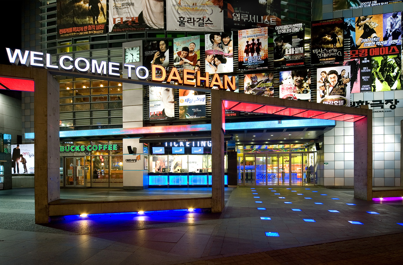 영화 포스터와 WELCOME TO DAEHAN 표지가 설치된 대한극장 입구 영화 포스터가 빽빽하게 걸린 외벽과 WELCOME TO DAEHAN 표지가 보이는 대한극장 입구